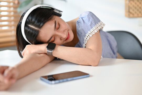 Relaxed Young Asian Female Fall Asleep At Her Desk While Listening To Music