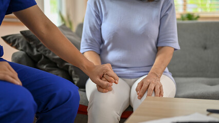 Close-up image of a kind doctor holding or touching a patient's hand to comfort