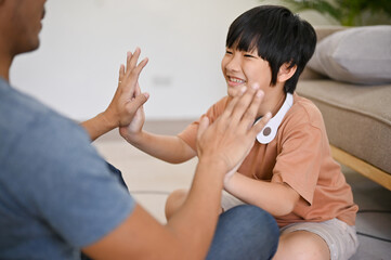 Cute Asian little boy playing with his dad, spending fun family games time in the living room