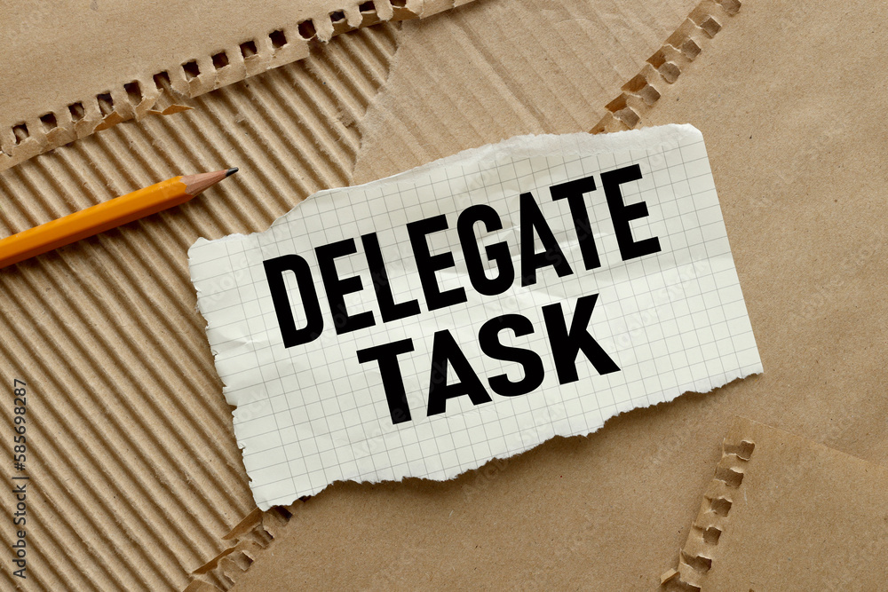 Poster delegate tasks text on torn paper on craft paper background. pencil points to text