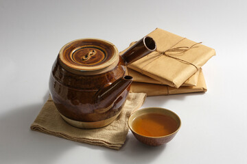 An earthen pot with a bowl of medicine placed on white background with some packs of traditional medicine. Natural medicine content