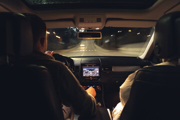 Man and woman in a car at night, view from the car.