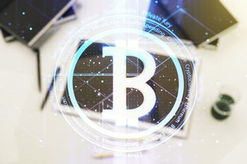 Double exposure of creative Bitcoin symbol hologram and modern digital tablet on background. Mining and blockchain concept