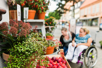 Woman with disability and her assistant choosing flowers in flower shop
