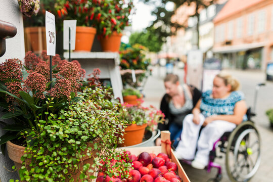Woman with disability and her assistant choosing flowers in flower shop