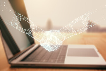 Double exposure of blockchain technology with handshake hologram on laptop background. Research and...
