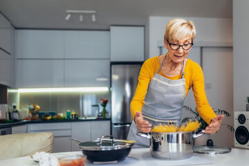 Happy senior woman cooking in her modern kitchen