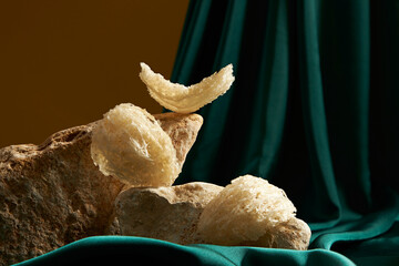 Some raw edible bird’s nest set on rock, on green soft fabric and brown background. Bird's nest...