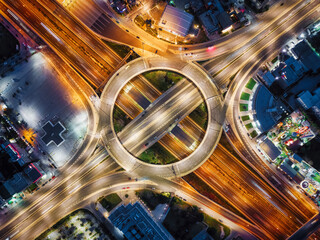 Aerial top view of a illuminated multilevel junction ring road as seen in Attiki Odos toll road motorway interchange with car traffic in Athens, Greece, during night time