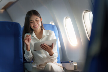 Beautiful Asian businesswoman working with digital tablet in aeroplane. working, travel, business concept