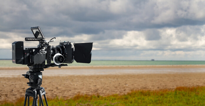 Digital movie camera making film in nature. 
a video camera films on a beach. Wide background with copy space for documentary production.