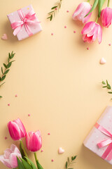 Mother's Day concept. Top view vertical photo of pink gift boxes with ribbon bows bouquets of tulips and heart shaped sprinkles on isolated pastel beige background with empty space on the middle