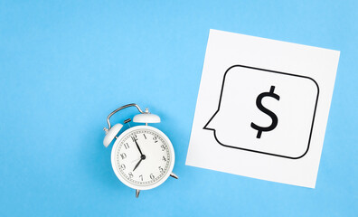 White alarm clock and dollar sign on a blue background, flat lay.