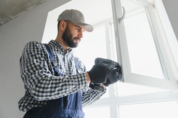 Naklejka na ściany i meble Worker in installing white plastic upvc window on house.