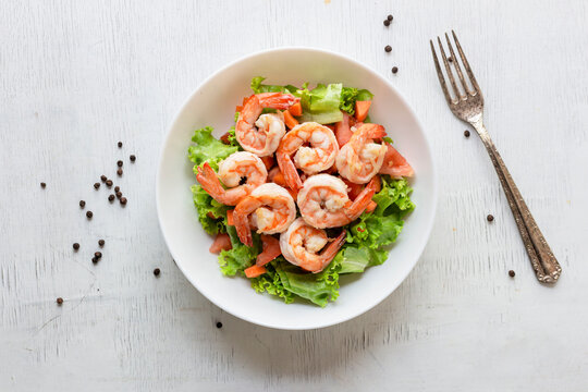 Healthy food shrimp salad lettuce carrot tomato in bowl on wood background.