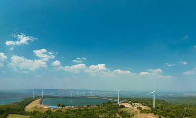 aerial view above a Group of Wind turbine on mountain at day time in Lam Takong Dam, Nakhon Ratchasima, Thailand
white cloud in blue sky background.Wind power generates electricity. Clean energy from 