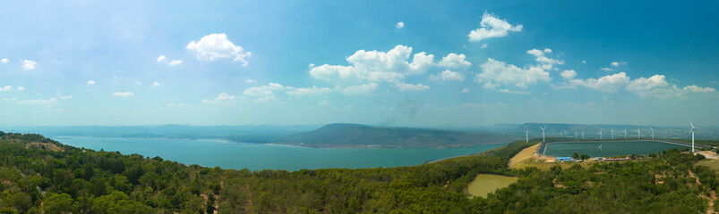 aerial view above a Group of Wind turbine on mountain at day time in Lam Takong Dam, Nakhon Ratchasima, Thailand
white cloud in blue sky background.Wind power generates electricity. Clean energy from 