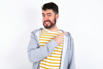 Young caucasian mán wearing trendy clothes over white background Pointing aside worried and nervous with forefinger, concern and surprise concept.