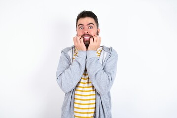 Fearful Young caucasian mán wearing trendy clothes over white background  keeps hands near mouth, feels frightened and scared,  has a phobia,  Shock and frighted concept.