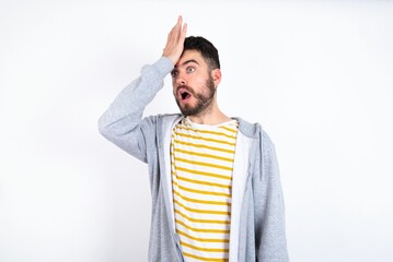 Young caucasian mán wearing trendy clothes over white background surprised with hand on head for...