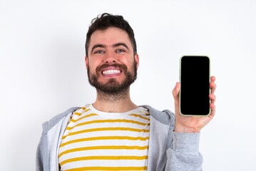 Smiling Young caucasian mán wearing trendy clothes over white background Mock up copy space. Hold mobile phone with blank empty screen