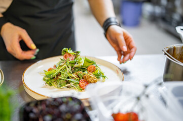 Chef cooking Caesar salad on restaurant kitchen