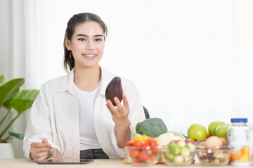 Happy female professional of nutrition healthful surrounded by a variety of fresh fruits and vegetables working on digital tablet and smiles. concept of right nutrition and diet, healthcare, diet.