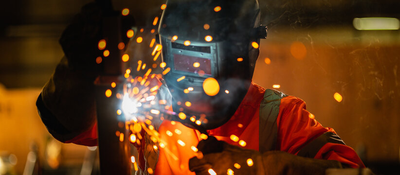 Panoramic workers wearing industrial uniforms using electric arc welding machine to weld steel at factory. Metalwork manufacturing and construction maintenance service by manual skill labor concept.