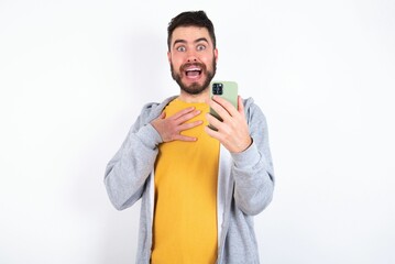 Smiling Young caucasian mán wearing trendy clothes over white background talks via cellphone, enjoys pleasant great conversation. People, technology, communication concept