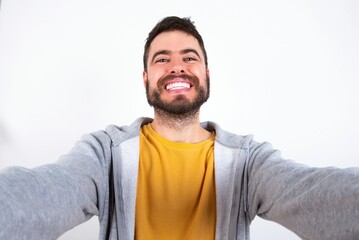 Photo of Young caucasian mán wearing trendy clothes over white background do selfie