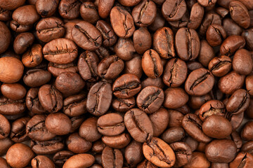 roasted whole arabica coffee beans, scattered on paper, isolated