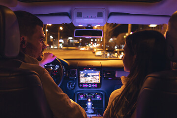 Man and woman in a car at night, view from the car.