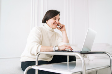 A happy person at work every day. A female psychologist consultant online uses a laptop in business clothes confident work in the office sitting in an armchair.