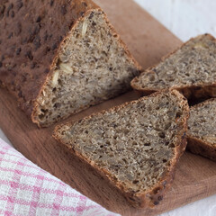 Sliced wholegrain bread in a form of triangle on a wooden board close up.