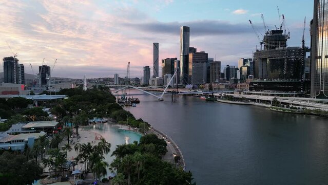 Drone shot of Brisbane City's South Bank Beach and Parklands. Camera stationary above South Bank Parklands. Brisbane River in background. Queens Wharf Casino and Neville Bonner Bridge in construction.