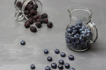 Blueberries in a decanter with water. Blackberries are scattered from a glass.