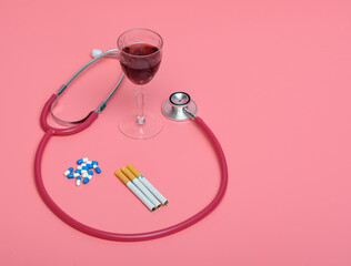 Stetoskop medyczny obok używek - alkoholu, papierosów i kieliszka z winem - obrazy, fototapety, plakaty