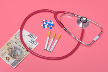 Papierosy rozrzucone na stole obok lekarstw, stetoskopu i pieniędzy 