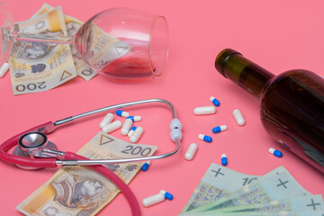 Przewrócony kieliszek, butelka wina obok pieniędzy, lekarstw i stetoskopu 
