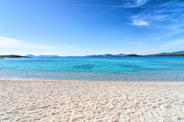 Mediterranean beach with white sand, turquoise transparent water and blue summer sky