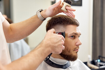 Barber trim hair with clipper on handsome bearded man