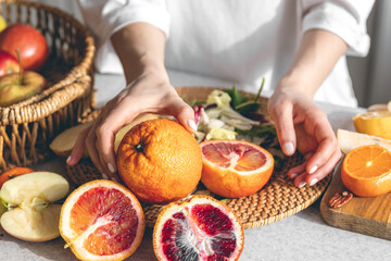 Oranges in female hands on the kitchen table, close-up.