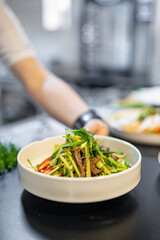 chef hand cooking Roast beef salad with vegetables on restaurant kitchen