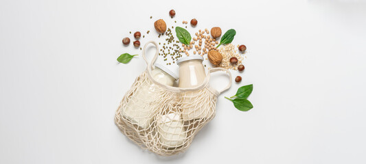 Variety of vegan plant based milk in zero waste mesh bag. Top view of lactose free milk based on nuts, legumes, oatmeal on white background