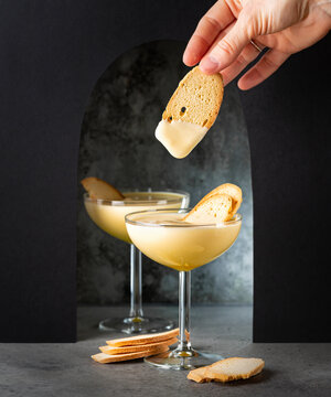 Eating Baicoli biscuit and zabaione zabaglione or sabayon in a champagne coupe. Italian cream-based dessert, made with egg yolks, sugar, and a sweet wine Marsala Light custard, whipped cream.