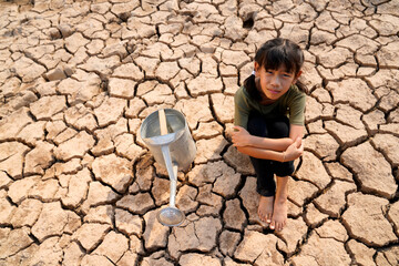 Sad kids are sitting on cracked earth open metal water old faucet on hot and dry empty land....