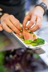 Chef decorate ready dish with slices parma ham on restaurant kitchen