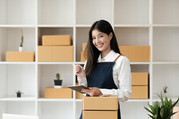 Portrait business Asian woman smile and use tablet checking information on parcel shipping box before send to customer. Entrepreneur small business working at home. SME business online marketing.