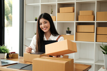 Obraz na płótnie Canvas Portrait of young Asian woman working SME with a box at home the workplace.start-up small business owner, small business entrepreneur SME or freelance business online and delivery concept.