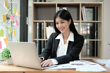 Millennial Asian happy cheerful pretty businesswoman secretary employee sitting smiling enjoy...